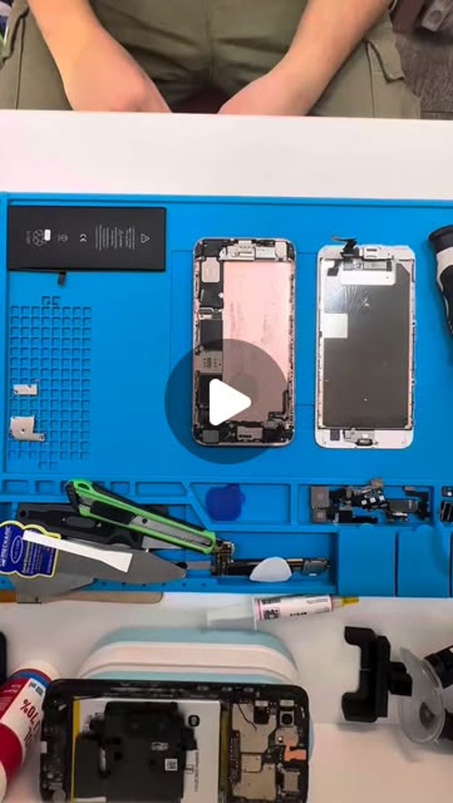 Still from an Instagram repair reel showing hands and a phone on a blue work mat
